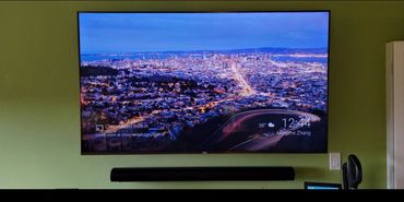 Wall-mounted TV displaying a cityscape at night with a soundbar below.