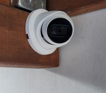 White security camera mounted on a wooden wall corner.