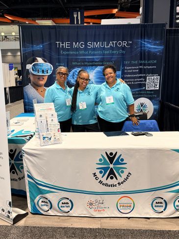 Three people at MG Holistic Society booth promoting the MG Simulator for Myasthenia Gravis awareness.