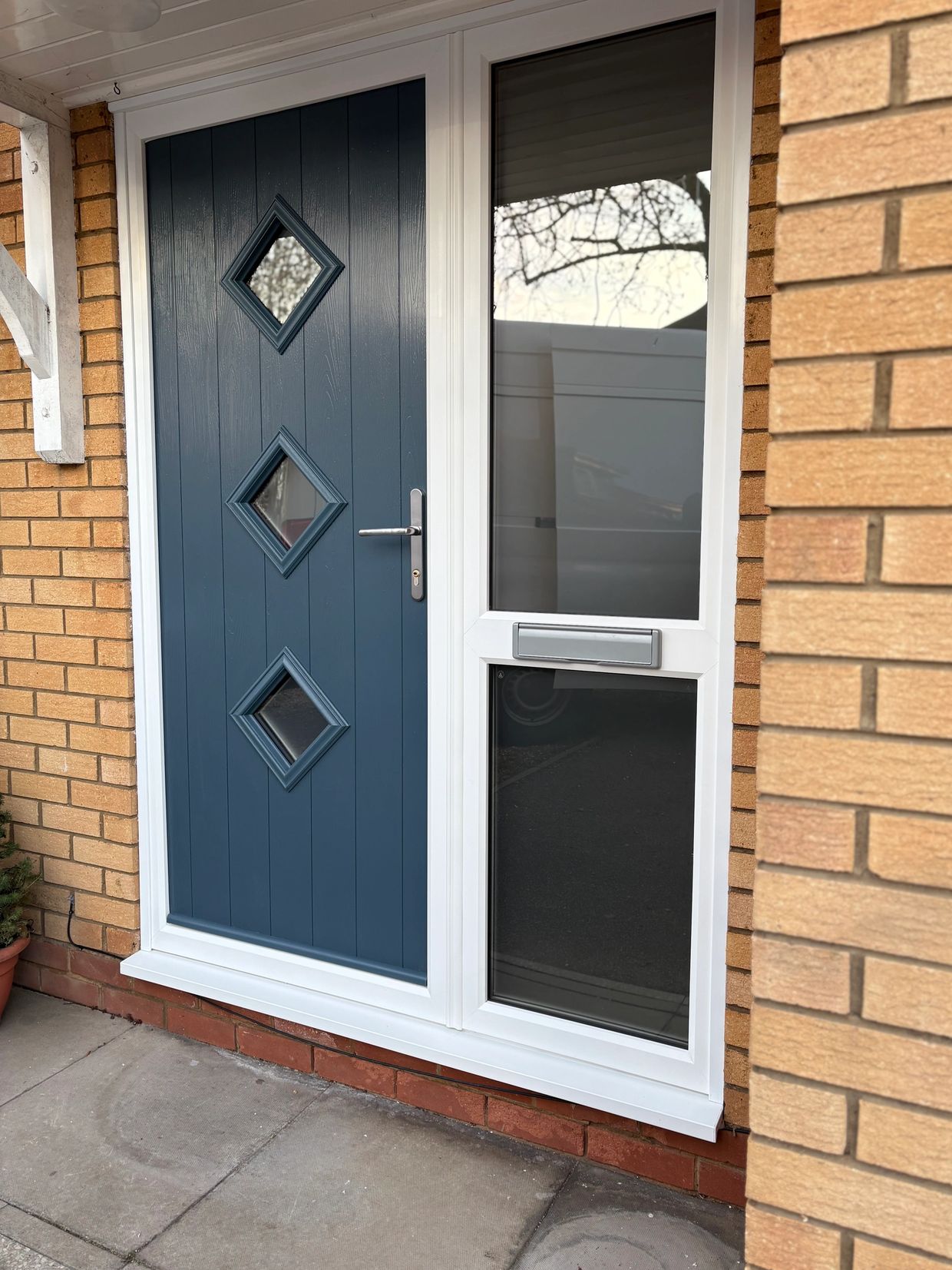 Blue front door with diamond-shaped windows and adjacent glass panel.
