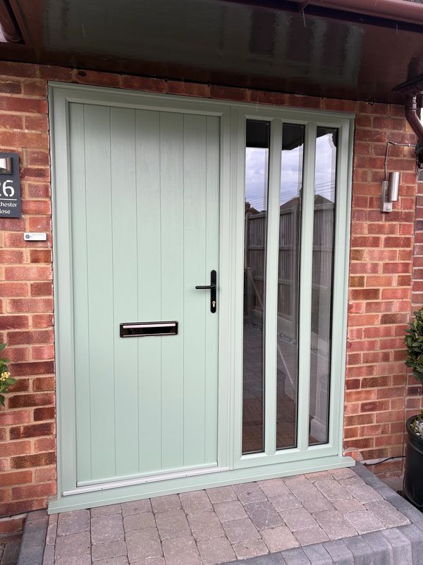 A mint green front door with vertical windows on a brick house.
