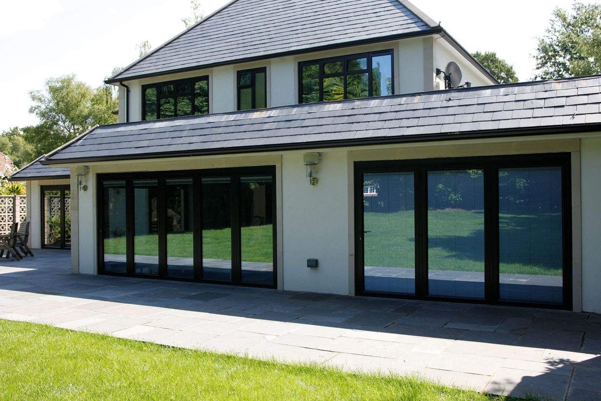 Modern house with large glass doors and a spacious patio area.