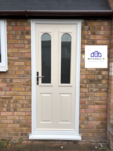 Cream-colored front door with two vertical glass panels on a brick house.