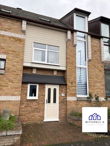 Modern brick house with white door and windows under cloudy sky.