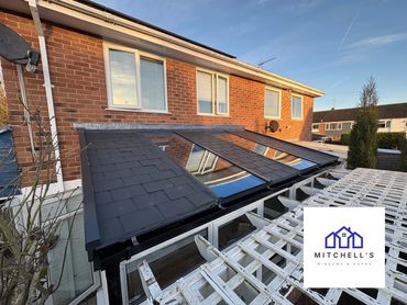Modern conservatory roof with glass and tiles on a brick house.