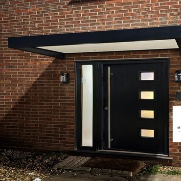 Modern black front door with frosted glass panels and a metal handle.