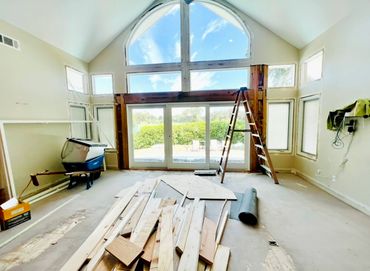 Room under renovation with large windows and construction materials.