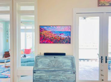 Bright room with vintage blue desk and colorful coastal artwork on the wall.