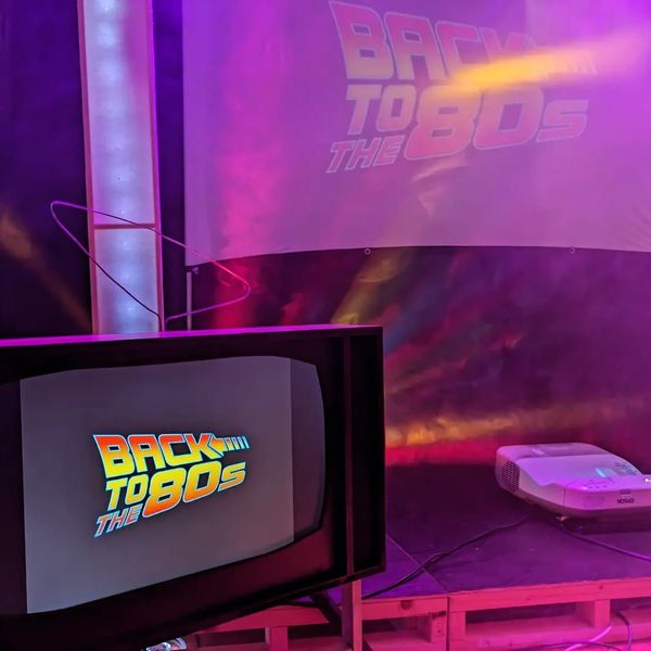 Retro-themed event with "Back to the 80s" display on TV and screen.