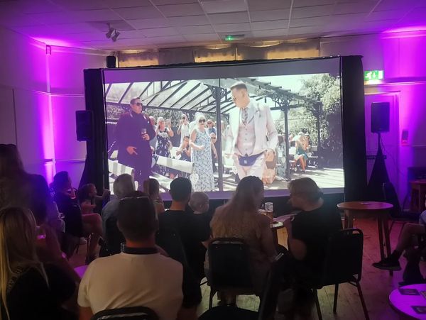 Audience watching a film in a purple-lit room.