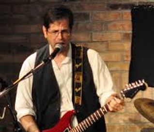 Man passionately playing an electric guitar on stage.