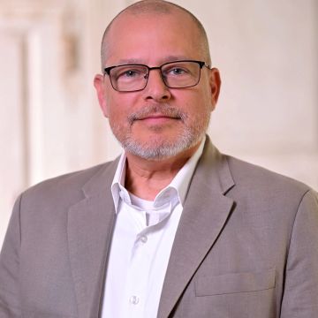 Middle-aged man in glasses and beige blazer.