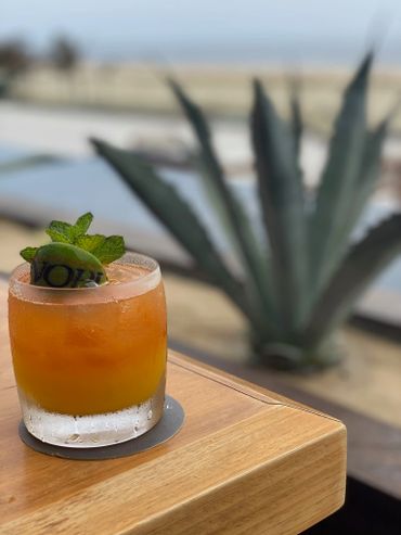 A refreshing orange cocktail garnished with mint and lime on a wooden table.