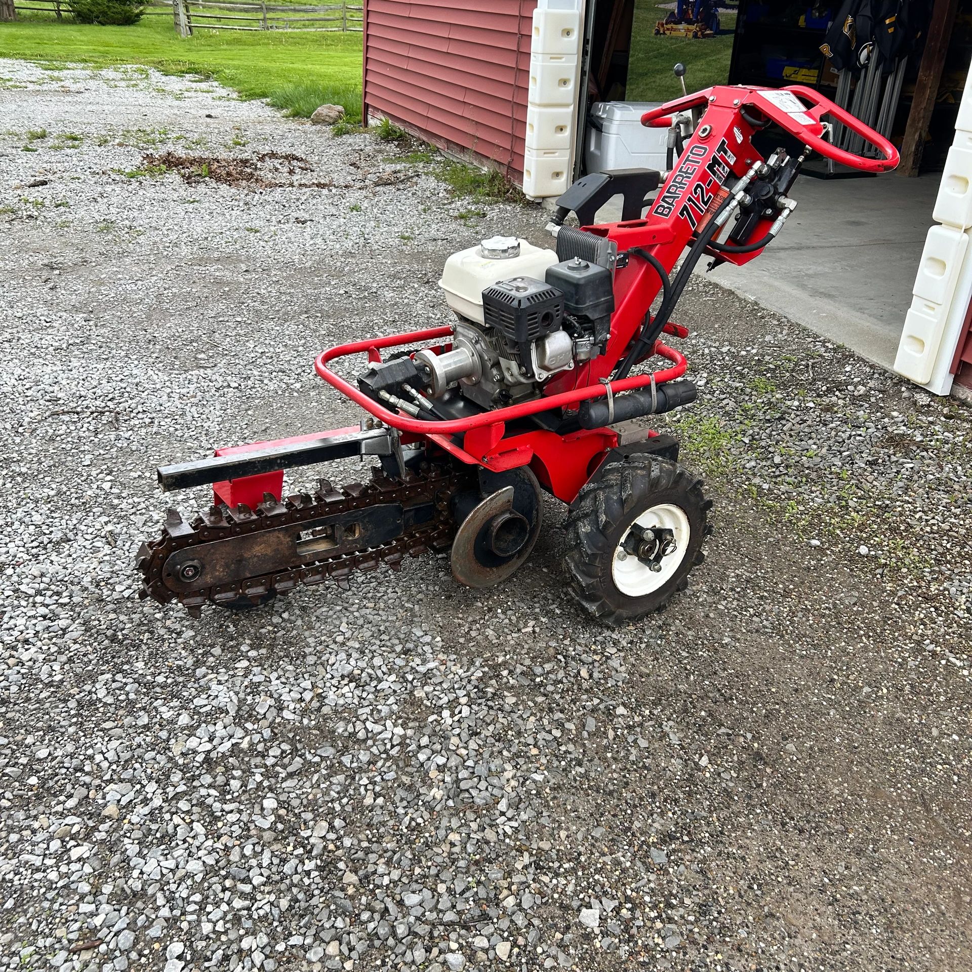 A red Barrett 712-MT trencher with a gas engine on a gravel driveway.