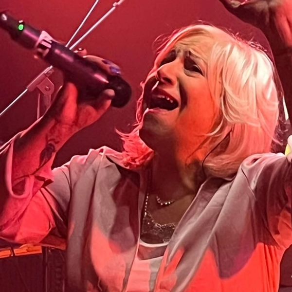 A passionate singer performs intensely on stage with a microphone.