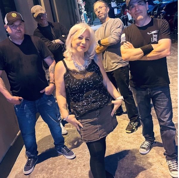 A group of five people posing confidently outdoors at night.