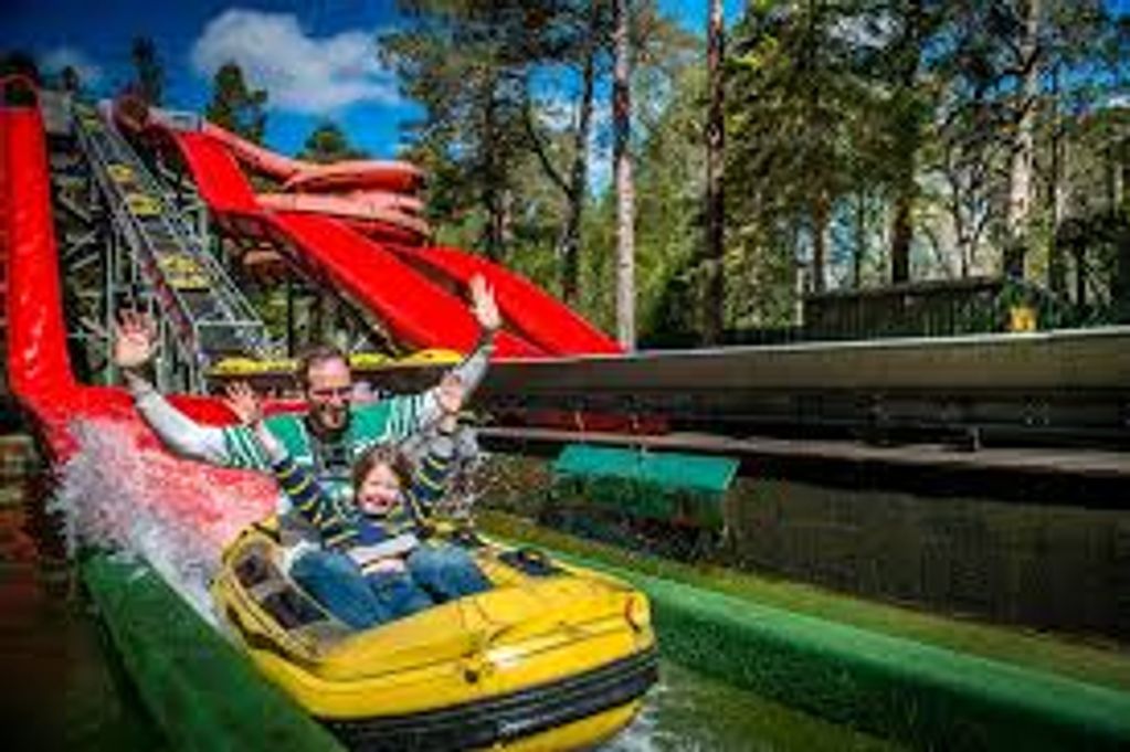 Two people enjoying a water slide ride in an amusement park.