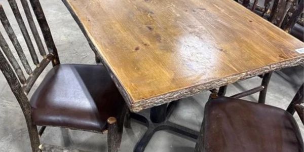 Rustic wooden table with matching chairs featuring dark leather seats.