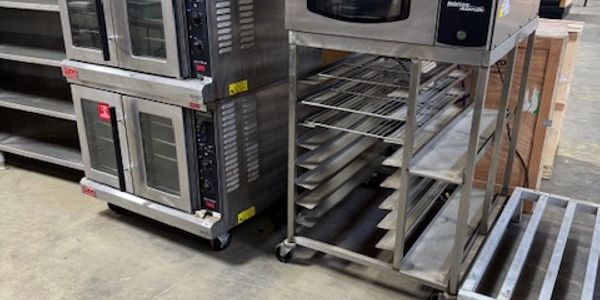 Commercial ovens and stainless steel racks in a warehouse setting.