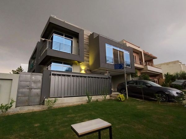 Modern two-story house with a sleek design and a black car parked outside.