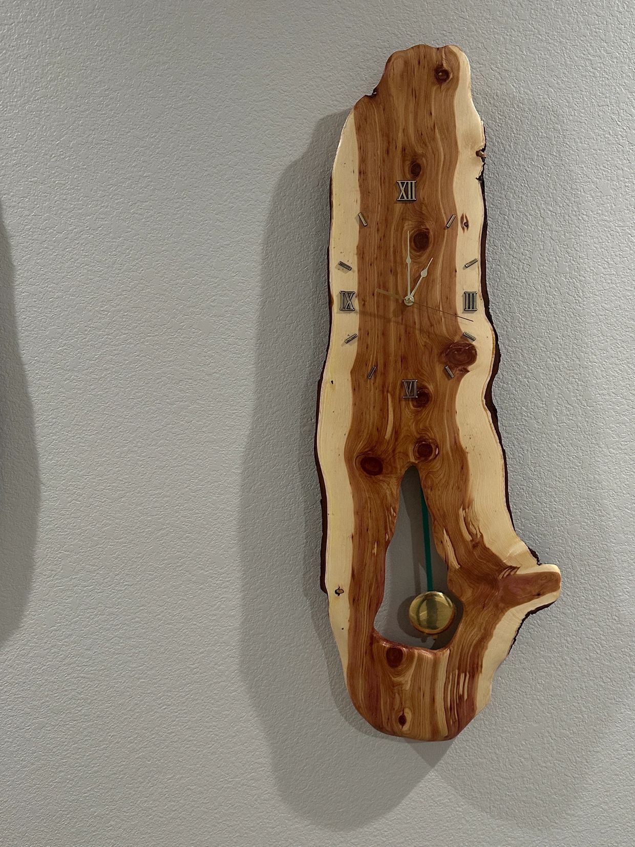 Wooden wall clock with Roman numerals and pendulum.