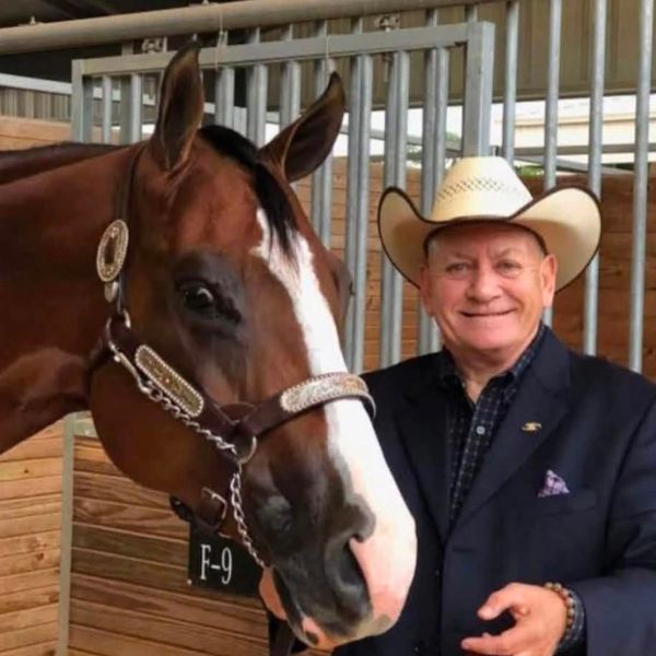 Man in a cowboy hat standing next to a horse.