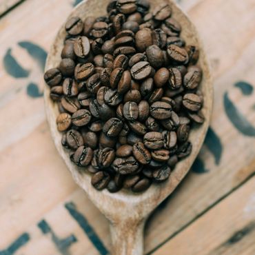 Close-up of roasted coffee beans in a wooden spoon.