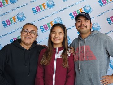 An image of a foster family taking a picture with the SDFF backdrop.