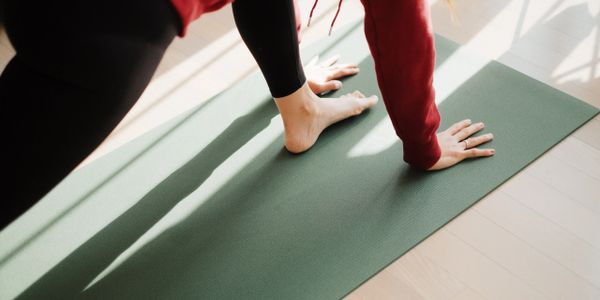 Person practicing yoga on a mat in sunlight.