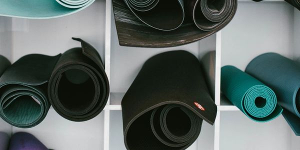 Rolled-up yoga mats stored on white shelves.