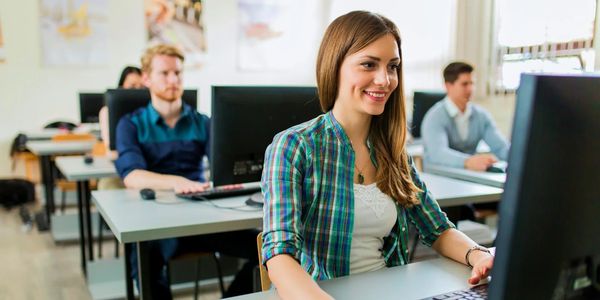 Young woman working on computer in a classroom with others.