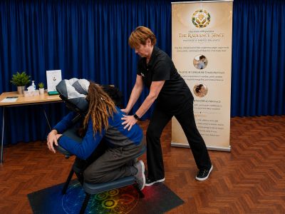 A therapist giving a seated acupressure massage to a client in a calm room.