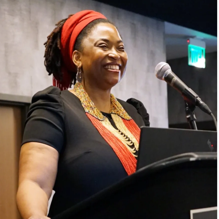 Smiling woman speaking at a podium with a microphone.