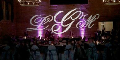 picture of an LGM monogram with purple uplights on a textured limestone wall.