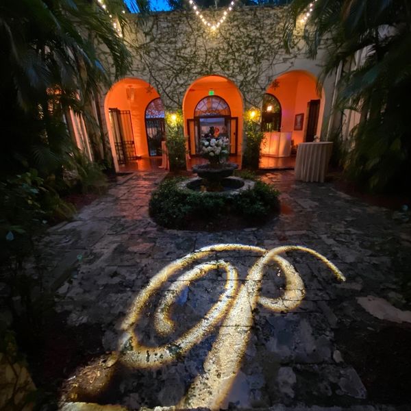 Picture of The Villa Woodbine Courtyard with Amber Uplights and a scripted "P" monogram at night. 