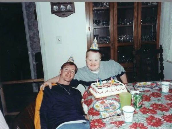 Two people wearing party hats celebrating a birthday with cake.