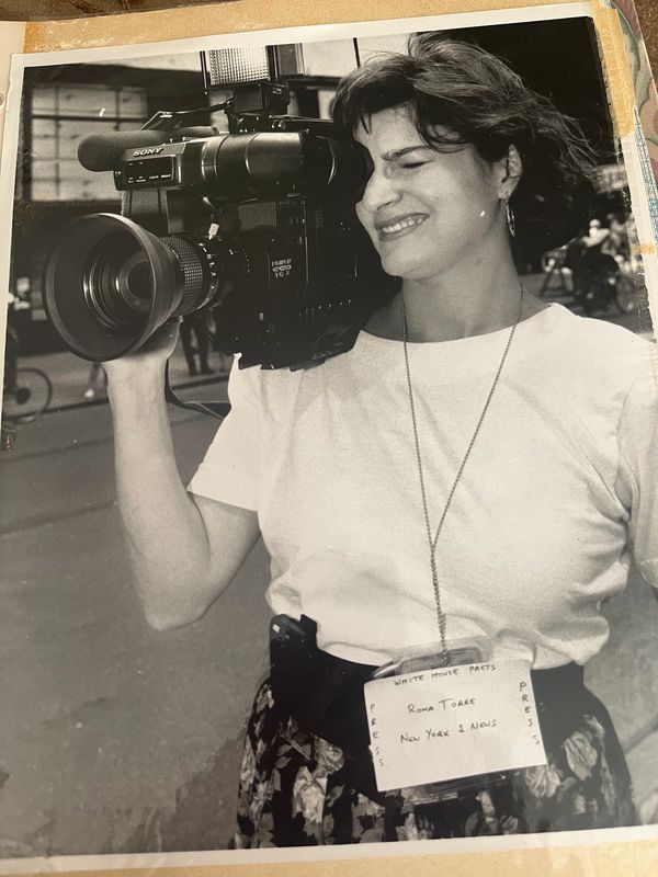 Woman smiling while holding a vintage video camera.