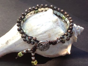 Beaded bracelet with green and brown beads on a shell.