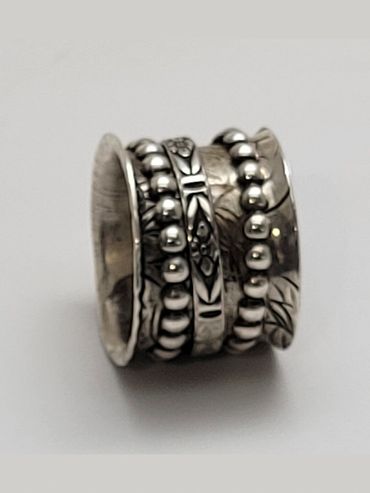 A detailed silver ring with intricate bead and floral patterns.