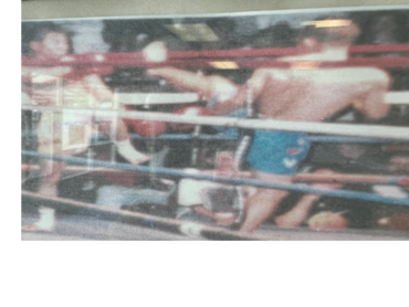 Blurred image of a boxing match with two fighters and a referee.