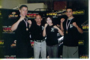 Four people posing with fists raised, two wearing medals.