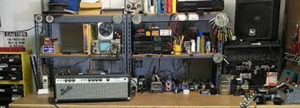A cluttered workbench with electronic equipment, tools, and components.