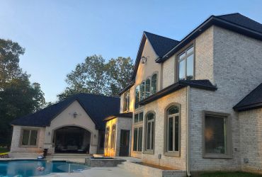 Modern brick house with a pool at sunset.