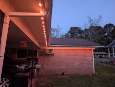 House exterior with string lights and car at dusk.