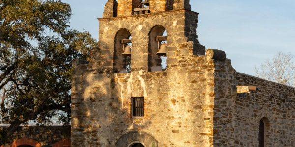 Historic stone building with bells at sunset light.