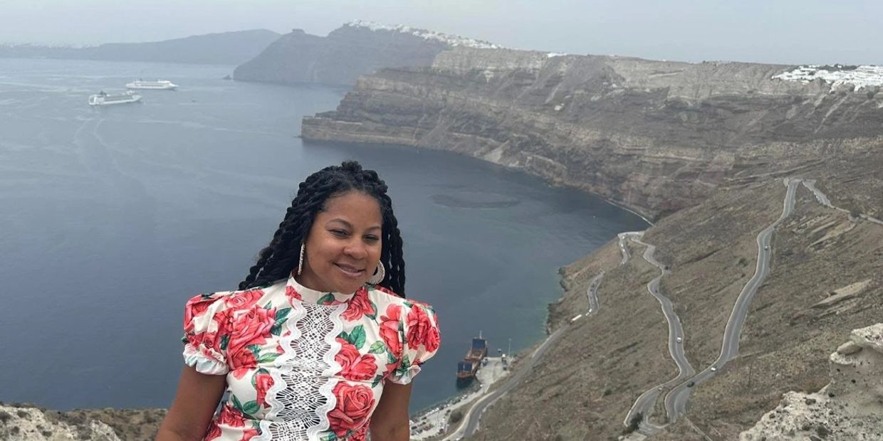 Woman smiling with scenic cliff and sea view.