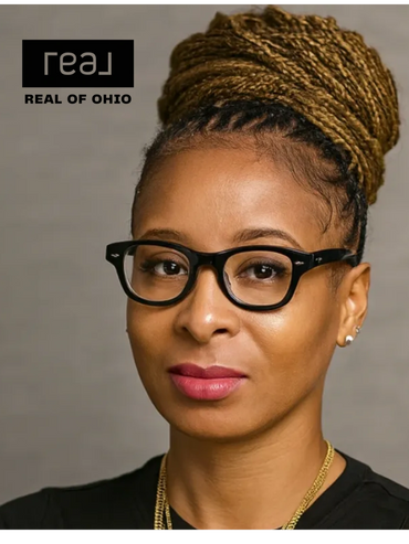 Confident woman with braided hair and black glasses, wearing gold necklaces.