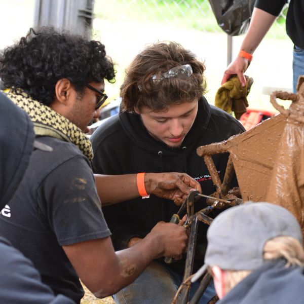 People working on a muddy mechanical project.