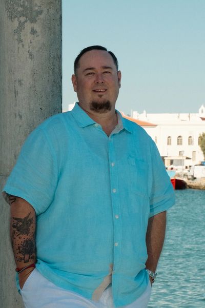 Mike leaning against a pillar in Mykonos Old Town with Mykonos i