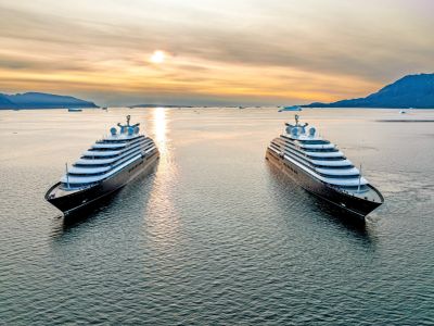 Two luxury yachts on calm water at sunset.